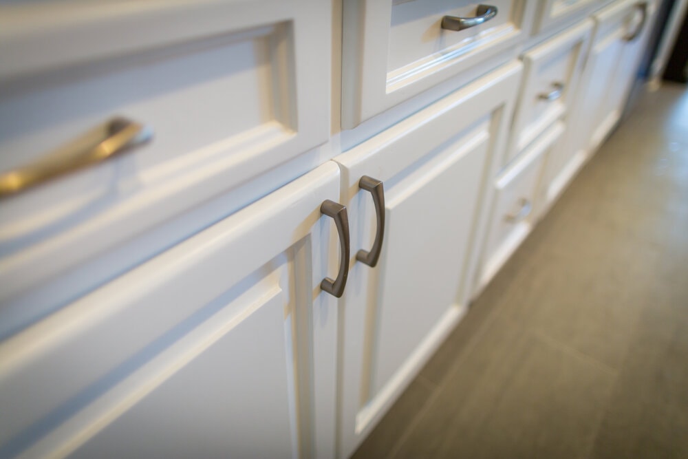 Original oak kitchen cabinets with a warm honey-toned finish and raised‐panel doors, fitted with tarnished brass hardware